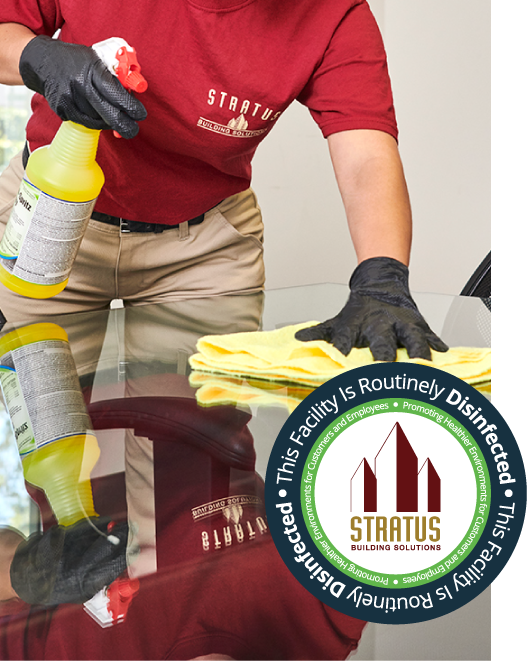 Stratus Building Solutions franchisee wiping down a conference table using a yellow microfiber cloth. 
